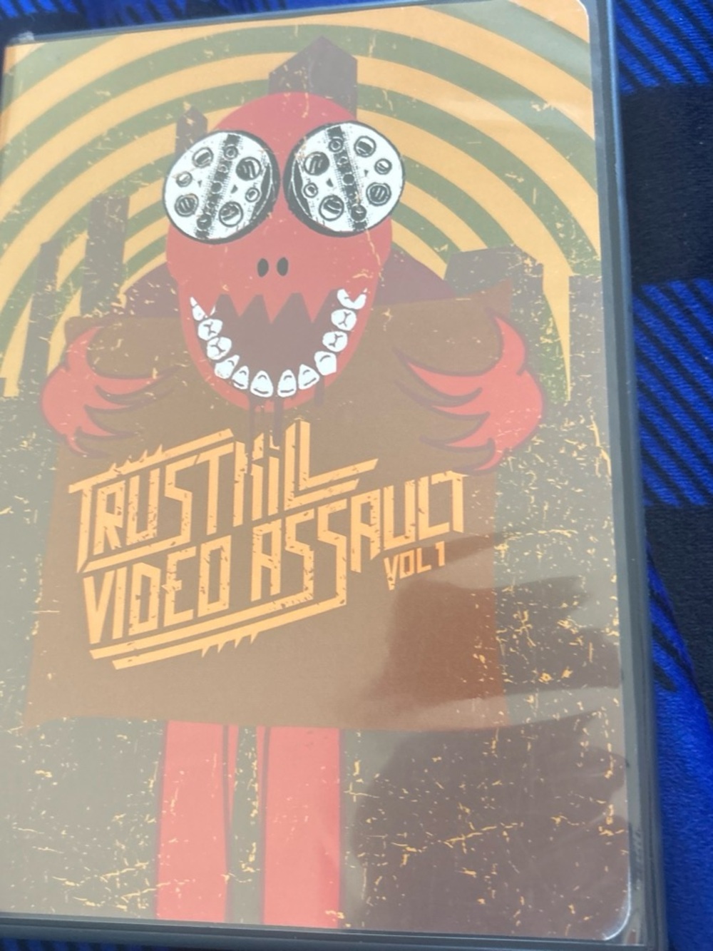 Trustkill records  Video Assault Vol. 1
Red cartoonish character with film reels